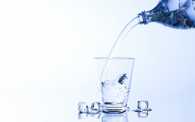 Pour water or clean water from a plastic or PET bottle into a drinking glass with ice cubes. Cold drinking water to quench thirst and refresh. 3D rendering