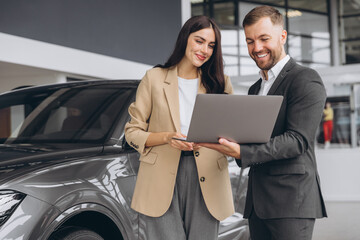 Male car salesman, recommends a car to a woman buyer, inspects cars in the showroom, the seller...