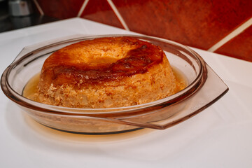 A dessert in a glass bowl with a yellowish color. The dessert is a cake with a yellow frosting