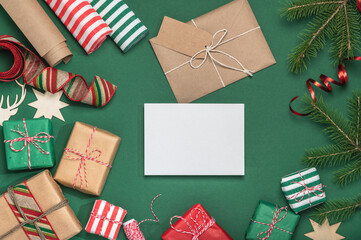 Fototapeta premium Christmas greeting card, background with fir branches, paper gift boxes and envelope. DIY gifts.