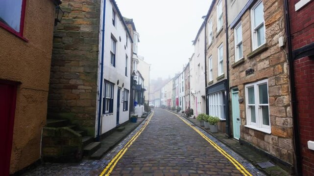 People walking along the quite streets of Staithes a sleepy fishing village on the Yorkshire coast of England. With cobbled streets and old stone built houses. Harbor walls and friendly public houses.