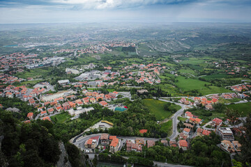Fototapeta premium Panoramic view of the lush landscape and charming towns of San Marino under an overcast sky