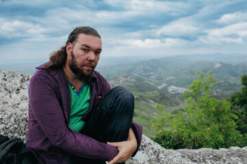 Tourist enjoying a moment of reflection on a rocky outcrop in San Marino on a cloudy day