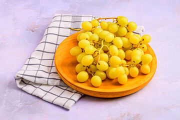 Bunch of Green Grapes on Wooden Plate over Light Marble
