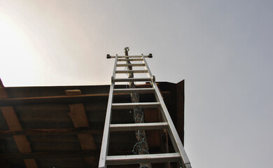ladder to the sky. high ladder on the edge of the roof view from below