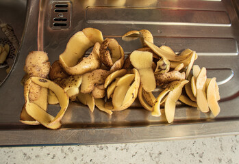 Raw peeled potatoes and peeled potatoes at the sink in the kitchen