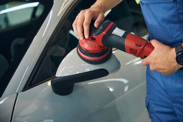 Man polishes the side mirror of a car