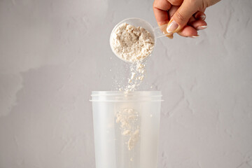 Protein powder in a scoop. Pouring chocolate protein powder in a shaker. Food supplement.