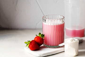 Pink protein drink shake, and protein powder in a scoop. Food supplement.