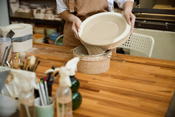 Cropped photo of woman making a clay plate while using special mold