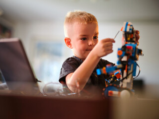 A small child, deeply focused in the act of assembling a colorful robotic device, creating an atmosphere of ingenuity and patience in the cozy home on this sunny day.