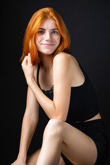 Naklejka premium Cute red-haired girl, studio portrait on a black background.