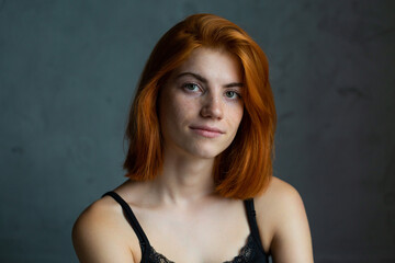 Cute red-haired girl, studio portrait on a black background.