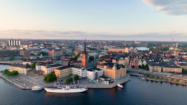 Aerial footage highlights a vibrant cityscape by serene water Riddarholmen Church, Stockholm City Hall. Sweden