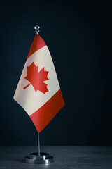 Tabletop flag Canada on a dark background, symbolizing Canadian identity and national values.