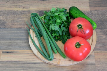 a wooden tray with vegetables and tomatoes on it