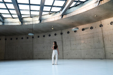 Woman walking in a large museum area with empty walls. Young woman walking in the empty gallery