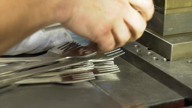 Slow Motion of hands punching tines in forks in a factory in Germany