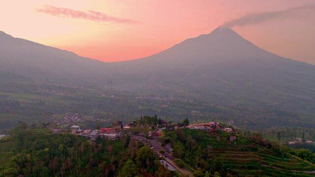 Aerial view of Hill with beautiful scenery of two mountains and sunrise sky on the background. Ketep Pass tourist attraction in the sunny morning and Mount Merbabu, Merapi Volcano on background.