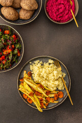 Enjoy a hearty breakfast or lunch with millet, baked zucchini, and carrots, paired with a fresh salad of seasonal vegetables and herbs, chickpea buns, beetroot hummus for a delicious vegetarian meal