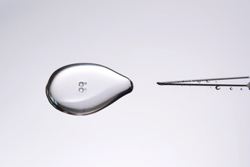 A drop of medicine flowing from a syringe with a needle.
