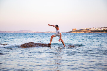 Man exploring coastal rocks in the sea, steps over rocks