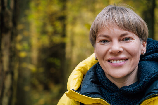 Smiling blonde woman enjoying autumn forest walk