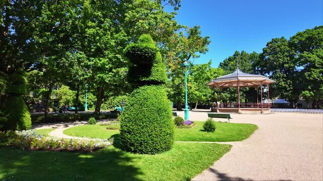 Part view at summer in the famous and public Thabor Park or Parc du Thabor with bandstand in background, Rennes, France. First-person walking backward