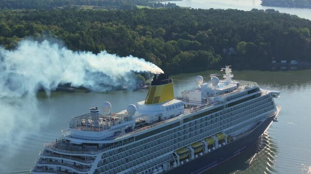 Cruise ship sailing in Finnish archipelago. Toxic emissions and lot of smoke from funnel. Aerial stern view. Maritime air pollution concept.
