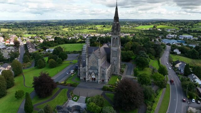 St. Macartan's Cathedral, County Monaghan, Ireland, September 2022. Drone ascends pulling backward showcasing the Gothic Revival facade with cloud shadows passing over the ornate stone architecture.