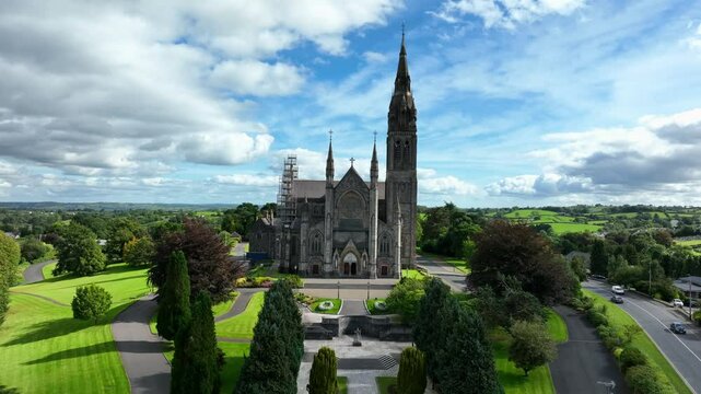 St. Macartan's Cathedral, County Monaghan, Ireland, September 2022. Drone slowly pulls backward showcasing the Gothic Revival architecture surrounded by Monaghan town with busy roads on both sides.