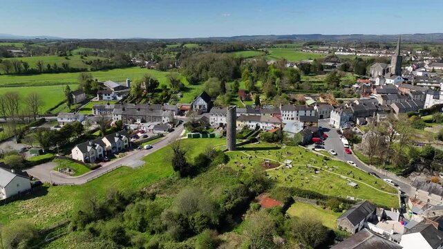 Round Tower, Clones Town, County Monaghan, Ireland, April 2023. Drone orbits the 10th Century Monastic building clockwise while slowly descending with St Tiarnach's Church of Ireland in the distance.