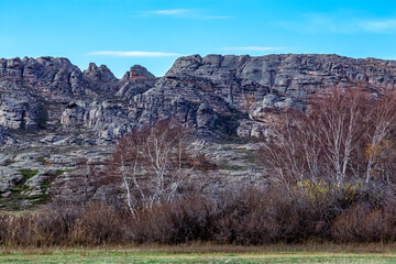 Stone mountains in layers with trees in the foreground in the great Kazakh steppe