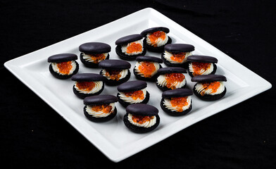 Black macarons with cream cheese and red caviar.