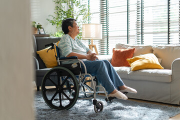 asian senior retired woman sitting on wheel chair in living room at home.Sad or depressed Elderly...