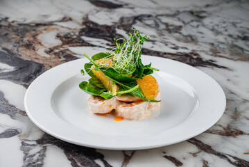 King prawns in cream sauce with oranges, spinach and microgreens in a plate.