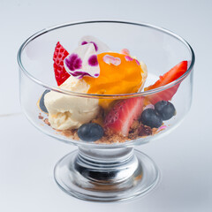 Cream cheese with mango sauce, strawberries, blueberries and crushed biscuits on a white background.