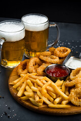 Set of fried onion rings, breaded squid rings, French fries and sauces with fresh beer.