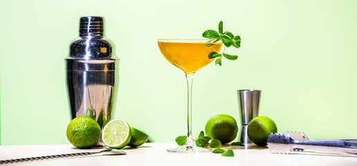 Summer alcoholic cocktail drink with rum, lime juice, dry sparkling wine, syrup, bitter, mint and ice, green background, hard light