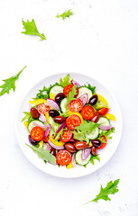Vegan vegetable salad with olives, tomato, paprika, cucumber and onion, healthy mediterranean food. White background, top view