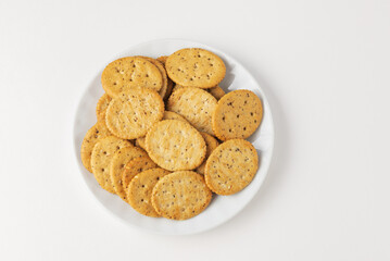 Oval crispy cookies or crackers on white plate on lisolated  on white background, top view with copy space