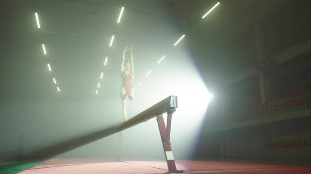 Woman performing gymnastics in the hall under strong lights