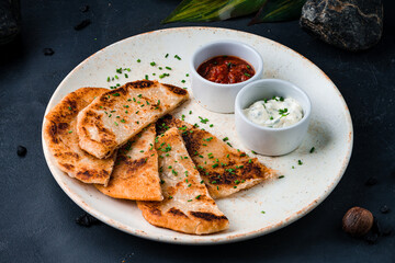 Mexican fried tortillas with sour cream sauce and tomato salsa.