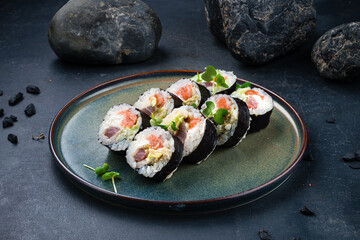 Sushi rolls with tuna, salmon, Philadelphia cheese, avocado and microgreens on a plate.