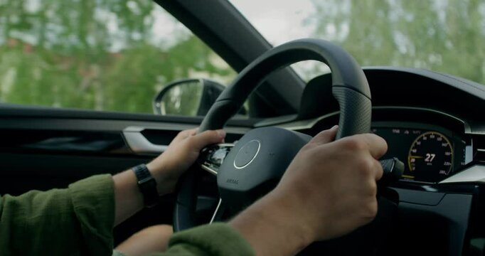 A man drives a car. Close-up of his hands, an unrecognizable person. View from the car interior. Summer day