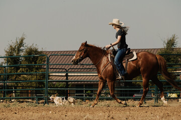 Western horseback riding shows cowgirl on horse in outdoor arena on Texas ranch.