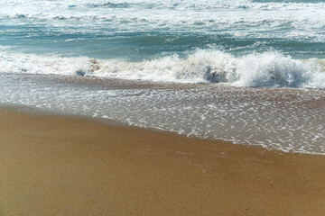 Yellow sand and foamy waves of the Atlantic Ocean.