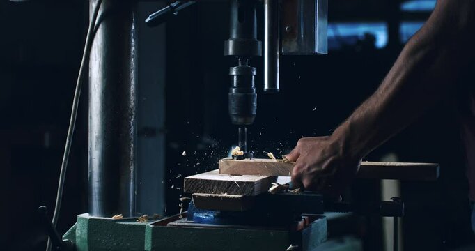 Super slow motion close up of carpenter working wood plank with carpentry equipment with flying chipping shaving pieces and  sawdust at workbench at industrial factory at 1000 fps.