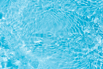 Blue water with ripples on the surface. Defocus blurred transparent blue colored clear calm water surface texture with splashes and bubbles. Water waves with shining pattern texture background.