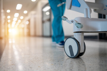 A hospital hallway with a nurse pushing a cart © EmmaStock